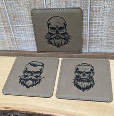 two leather coasters with skulls and beards on them, sitting on a table