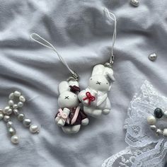 two white teddy bears sitting on top of a bed next to pearls and laces