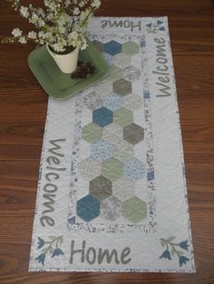 a table runner with a potted plant on it and the words welcome home written in large letters