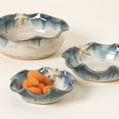 three ceramic bowls with starfish designs and oranges in the bottom one is empty