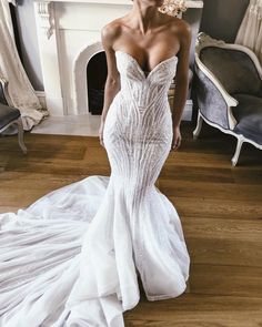 a woman in a white wedding dress standing on a wooden floor next to a fireplace