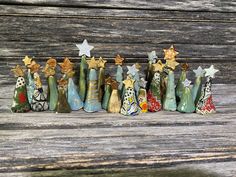 small ceramic christmas trees lined up against a wooden surface with stars on top and one standing out from the crowd