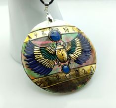 Mother of pearl sacred Egyptian Scarab necklace painted directly on mother of pearl for a 3D perspective Ancient Egypt's sacred blue and gold color (gold leaf) with hieroglyphic inscriptions Protection charm Absolutely jaw-dropping and one of a kind Entirely hand painted and hand made, signed Atlantic mother of pearl, thick shell Mother of pearl back D.6cm Jewellery cord full length approx. 60cm, adjustable Lobster claw clasp Spiritual Mother Of Pearl Pendant Necklace, Gold Abalone Shell Necklace In Unique Style, Unique Gold Abalone Shell Necklaces, Unique Gold Abalone Shell Necklace, Unique Gold Necklace With Abalone Shell, Unique Gold Jewelry With Abalone Shell, Gold Abalone Shell Pendant Jewelry, Spiritual Gold Necklace With Mother Of Pearl, Gold Mother Of Pearl Medallion Necklace