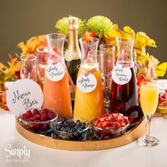 a tray filled with drinks and fruit on top of a table next to wine glasses