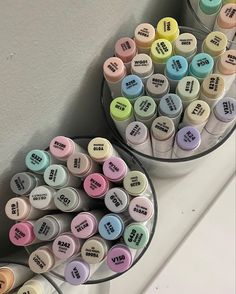 two bowls filled with different types of markers on top of a white counter next to each other