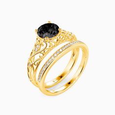 two gold wedding rings with an oval black diamond in the center and white diamonds on each band