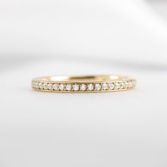 a yellow gold wedding band with small diamonds on the inside and outside, sitting on a white surface