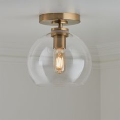 a light fixture with a clear glass globe on the top and an antique brass finish