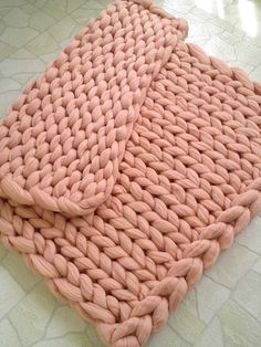 two pink knitted blankets sitting on top of a white tiled floor next to each other