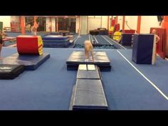 a woman is standing on the edge of a trampoline course in a gym