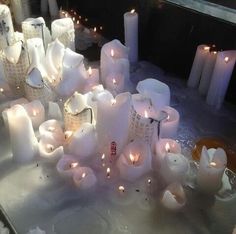 many lit candles are on the table in front of some other white ones and one is surrounded by smaller ones