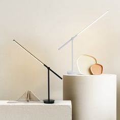 a table lamp sitting on top of a white pedestal next to a plate and cup