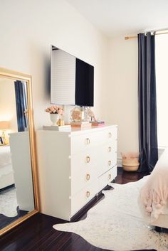 a bedroom with a dresser, mirror and television