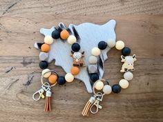 an assortment of beads and charms on a wooden table with a cow, horse, giraffe charm