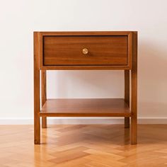 a small wooden table sitting on top of a hard wood floor next to a white wall