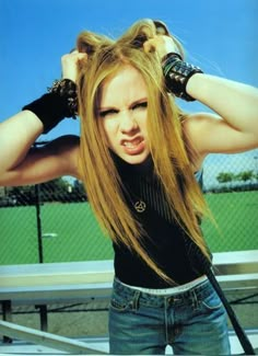 a woman with long blonde hair is holding her hands on her head and looking at the camera