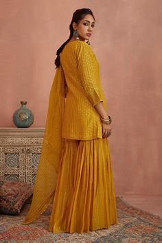 Yellow chanderi short kurta with thread embroidery. Comes with gharara and an organza dupatta.
Components: 3
Pattern: Embroidered
Type Of Work: Thread
Neckline: Notched
Sleeve Type: Three quarter
Fabric: Chanderi, Dupatta: Organza
Color: Yellow
Other Details: 
Length:
Kurta: 31 inches
Gharara: 42 inches
Note: Ivory outfit worn by the other model is not for sale.
Occasion: Mehendi and Haldi - Aza Fashions Unstitched Chinon Sharara With Straight Kurta, Unstitched Chinon Sharara For Navratri, Festive Straight Kurta Sharara With Dori Work, Festive Slub Silk Sharara With Chikankari Embroidery, Slub Silk Sharara With Chikankari Embroidery For Festivals, Slub Silk Sharara With Zari Work For Navratri, Straight Kurta Sharara With Resham Embroidery For Navratri, Chikankari Embroidered Slub Silk Sharara For Festivals, Festival Slub Silk Sharara With Dori Work