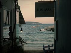 an open door leading to the beach with boats in the water and a sign that says thalasssa on it