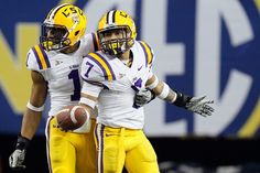 two football players standing next to each other with their arms around one another, both wearing yellow and white uniforms