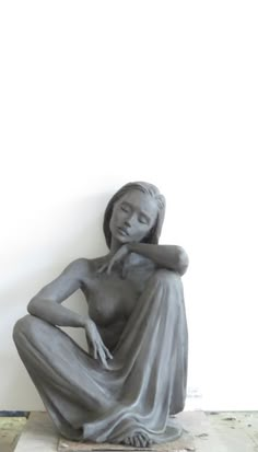 a sculpture of a woman sitting on the ground