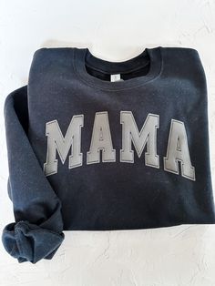 "The Mama Crewneck Sweatshirt is the perfect way to show your love and appreciation for the important mother figure in your life. This classic and comfortable sweatshirt will keep you warm and cozy all season long. Made of high-quality pre-shrunk cotton, it features a classic crewneck design with a a varsity style puff print \"MAMA\" logo on the chest. *Note, the puff print is black but appears dark grey on the black crewneck. The ribbed cuffs, hem, and neckline ensure a snug fit that will last. Whether you're lounging on the couch with mom or taking her out for an outing, this sweatshirt is sure to make her feel special and appreciated. ** PLEASE READ DESCRIPTION ** All sizes are UNISEX - check Size Chart in Listing Photos *Need a different size? Send us a message! We are in the process o Mother's Day Black Crew Neck Sweatshirt, Casual Black Sweatshirt For Mother's Day, Black Graphic Print Mother's Day Sweatshirt, Black Graphic Print Sweatshirt For Mother's Day, Mother's Day Black Graphic Print Sweatshirt, Puffy Vinyl, Mama Logo, Mama Crewneck Sweatshirt, Mama Crewneck