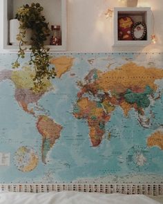 a bed with a map on the wall next to a potted plant and window