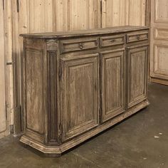 an old wooden cabinet in the corner of a room with wood paneling on the walls