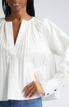 Accordion pleats fan out from the neckline, flaring the silhouette of this popover top framed with raglan sleeves with tailored-touch two-button cuffs. 22 1/2" length (size 2) Split neck Long sleeves with two-button cuffs 96% cotton, 4% elastane Dry clean Imported Designer Clothing Pleated Tops For Daywear In Fall, Classic Pleated Tops For Fall, Classic Pleated Blouse For Daywear, Classic Formal Tops With Gathered Sleeves, Fall Classic Pleated Tops, Daywear Tops With Cuffed Bishop Sleeves, Classic Pleated Office Tops, V-neck Pleated Sleeve Work Top, White Pleated Sleeve Top For Work