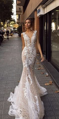 a woman is walking down the street in a wedding dress with an open back and lace detailing