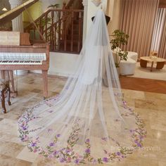 a bride's veil is draped over a piano in the living room with purple flowers