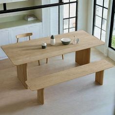 a wooden table with two benches in front of it and windows overlooking the outside area