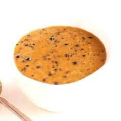 a white bowl filled with soup next to a spoon