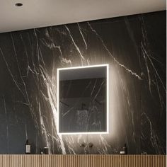 a bathroom with a sink, mirror and lights on the wall above it's counter