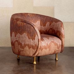 a brown and gold chair sitting on top of a cement floor next to a wall