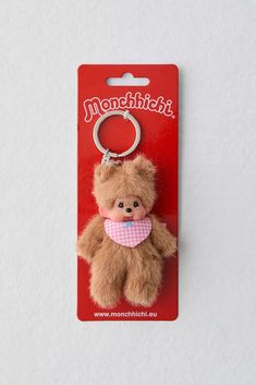 a brown teddy bear keychain with a pink bib around it's neck