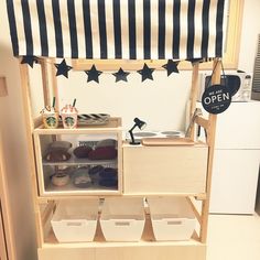 a kitchen with an open shelf and bins on the bottom floor, under a black and white awning