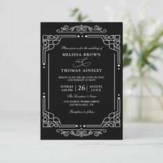 a black and white wedding card with an ornate frame on the front, featuring a monogramed design