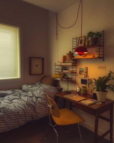 a bedroom with a bed, desk and shelves on the wall next to a window