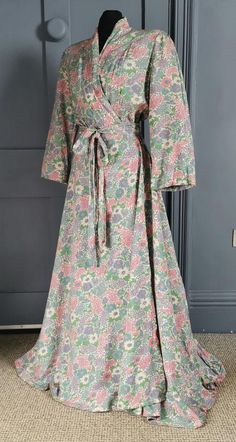 A fab vintage housecoat / dressing robe dating to the 1930s. One piece, off white cotton ( smooth and weighted handle, possibly a blend ? ) with a fantastic all over print of stylised Art deco flowers in greens, pinks and blues. The gown crosses over at the front, fastening with a snap on the inside and a snap on the outer, with a self belt attached at the back, loose at the front. The wide shoulders are shaped with darts, the sleeves wide, the skirt flaring to the floor in an elegant A line, lo Vintage Spring Robe For Home, Fitted Vintage Robe For Daywear, Vintage Cotton Home Dress, Vintage Long Fitted Robe, Vintage Spring Loungewear Robe, Spring Vintage Robe For Loungewear, Spring Cream Cotton Robe, Fitted Cotton Robe For Daywear, Spring Vintage Loungewear Robe