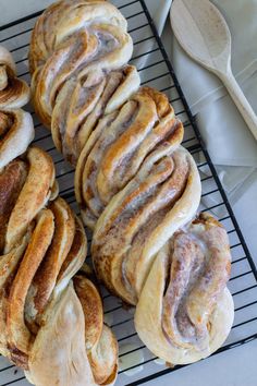 several cinnamon rolls sitting on top of a cooling rack next to a spoon and fork