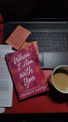 a book sitting on top of a desk next to a cup of coffee and an open laptop computer