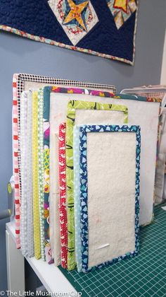 several quilts are lined up on a shelf in front of a wall art piece