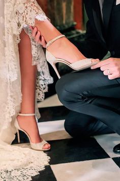 a man kneeling down next to a woman's shoe on top of a black and white checkered floor