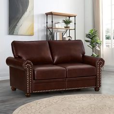 a brown leather couch sitting in a living room next to a book shelf and potted plant