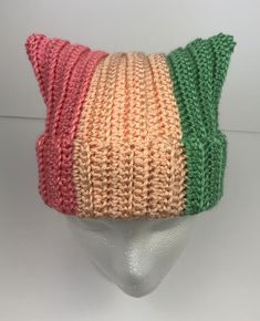 a white mannequin head wearing a knitted hat with multicolored stripes