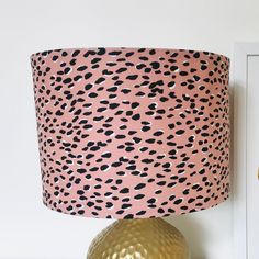 a pink and black leopard print lampshade next to a gold vase on a shelf