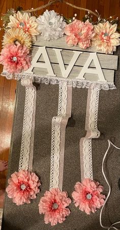 a wooden sign with flowers and lace on it