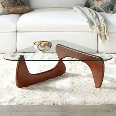 a glass coffee table sitting on top of a white rug in front of a couch