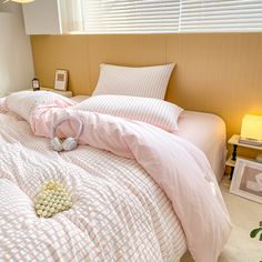 a bed with pink and white comforters in a bedroom next to a window,