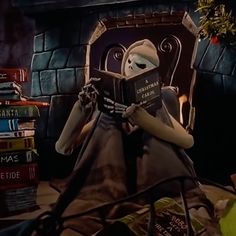 a woman sitting in a chair reading a book while wearing a mask and holding a stack of books